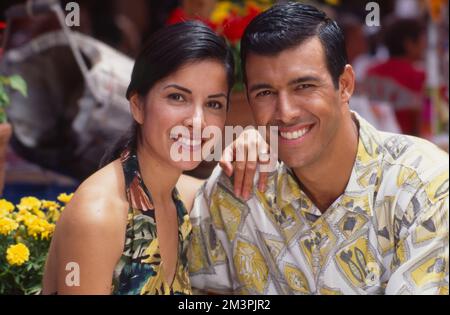 Young Hispanic couple in tropical clothes posing to smile at the camera Stock Photo