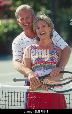 Middle aged couple pausing for a portrait while playing tennis Stock Photo