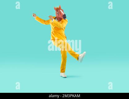 Man in a funny horse mask and a bright yellow suit is fooling around. Stock Photo