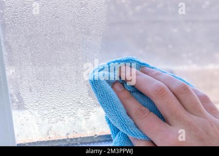 Condensation on windows in winter, wiping with a dry cloth Stock Photo