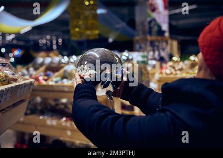 A woman holds in her hands a shiny Christmas ball reflected in the ball Stock Photo