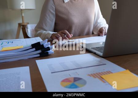 Cropped image of professional businesswoman, entrepreneur or accountant working on a financial report paperwork at her desk, using calculator, laptop Stock Photo