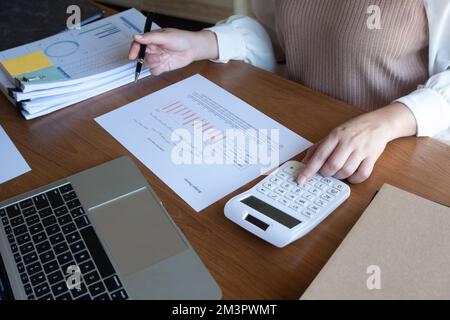 Cropped image of professional businesswoman, entrepreneur or accountant working on a financial report paperwork at her desk, using calculator, laptop Stock Photo