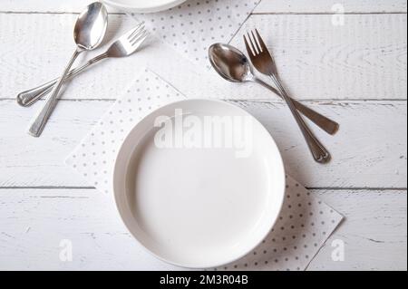 Empty white plate with fork and spoon on white background Stock Photo