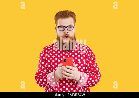 Funny fat bearded guy in glasses gets surprised by notification on his mobile phone Stock Photo