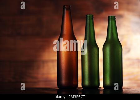 three colorful empty beer bottles on wooden background Stock Photo