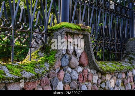 Old stone fence overgrown with green moss Stock Photo