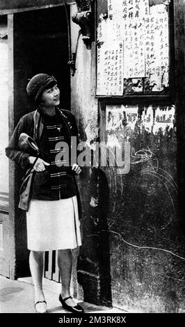 Chinese-American actress Anna May Wong (1905-1961) reads a menu in London's Chinatown in Limehouse.  1928 Stock Photo