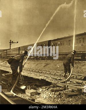 Firefighters working for Southern Railway spray water onto the roof of a train. Southern Railway employed eighty A.F.S. men in order to fight fires caused by Luftwaffe incendiary bombs.   1940 Stock Photo
