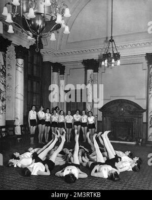 An exercise class of members of the League of Health and Beauty, comprising staff at the Ministry of Health in Whitehall.  They were allowed to use one of the conference rooms for an out of hours practice session.     Date: 1938 Stock Photo