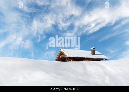 Small wooden log cabin on meadow Alpe di Siusi on blue sky background. Seiser Alm, Dolomites, Italy Stock Photo