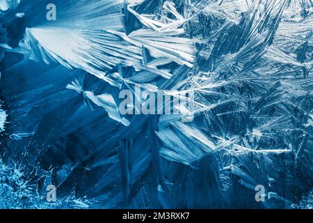 Christmas background with frozen pattern on window glass. Real blue texture of winter snowfrost Stock Photo