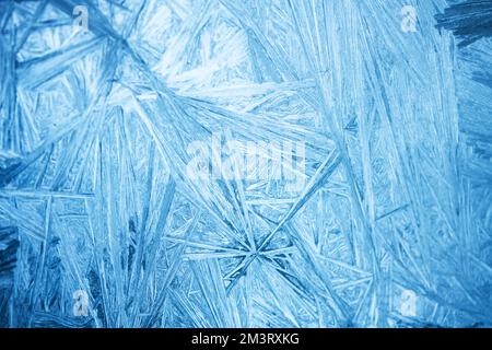 Christmas background with frozen pattern on window glass. Real blue texture of winter snowfrost Stock Photo