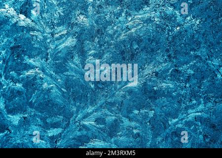 Christmas background with frozen pattern on window glass. Real blue texture of winter snowfrost Stock Photo