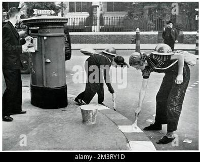Women painting kerbside for blackouts, September 1939 Stock Photo