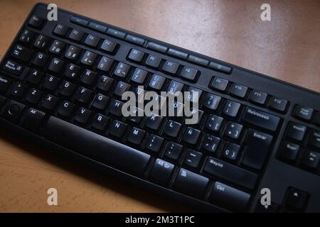 Flat lay view of a black multimedia keyboard with western characters on a wooden table Stock Photo