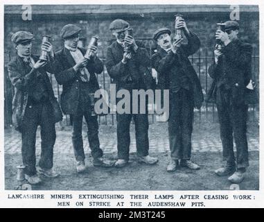 Lancashire miners extinguishing their lamps after ceasing work: Men on strike at Audenshaw pits. Stock Photo