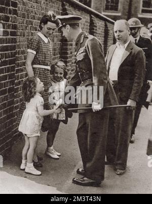 King George VI's visit to the bomb-shattered East End of London in September 1940: shaking hands with the little daughter, Joan Miles, of the caretaker of a school which was bombed. Stock Photo