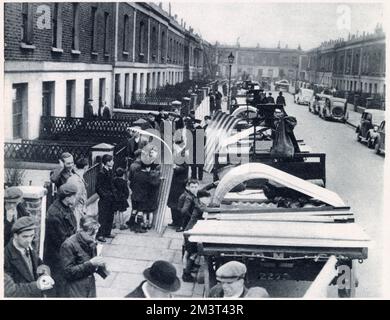 The first post-war delivery of the Government's steel for air-raid shelters in Tiber Street and Carlsbad Street, Islington, London. The sections were carried through the houses with much difficulty into the small backyards behind. The erecting of the shelters state that they had to be buried three feet in the ground and most of these where paved with concrete. Stock Photo