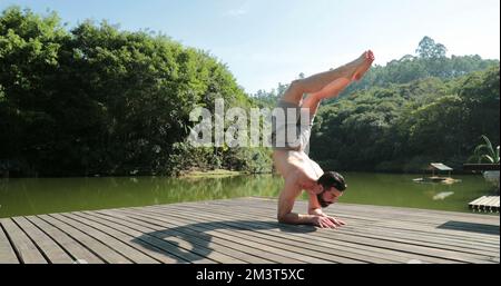 Person practicing Yoga outdoors in nature. Young man doing a hand-stand asana Stock Photo