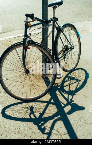 Vertical shot of a nice parked bicycle outdoors in the street on a sunny day. Stock Photo