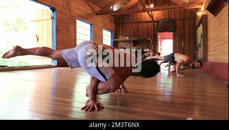 Yogi instructor teaching students advanced Yoga asana pose Stock Photo