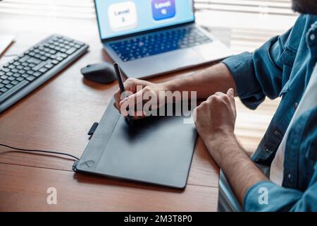 Male designer works in home office drawing on graphic tablet. Freelancer working on project Stock Photo