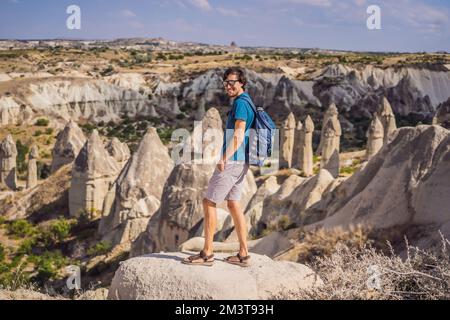 Young man exploring valley with rock formations and fairy caves near Goreme in Cappadocia Turkey Stock Photo