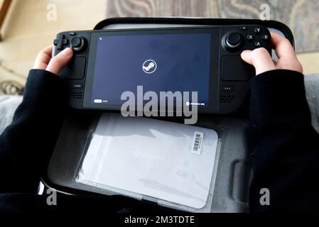 Lublin, Poland, 16 December 2022. young caucasian woman stariting Valve Steam Deck portable game console for the first timeL Stock Photo