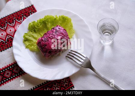 Dressed herring salad with a glass of horilka. Traditional Ukrainian food. Stock Photo