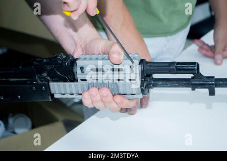 3D printed weapon parts. Man assembles weapon rifle, some parts printed on 3D printer. Details of gray color of weapon printed on 3D printer from polyamide powder. Progressive additive technology Stock Photo