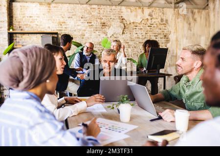 Mature man experienced in marketing strategy explaining to the work team the process of communication and advertising, people working in the world of Stock Photo