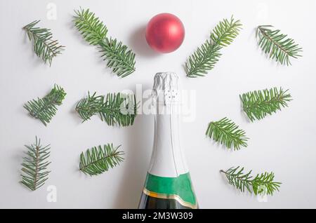 A bottle of champagne,red ball and many fir tree branches on white background.Top view,flatlay Stock Photo