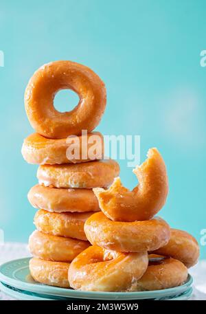 Stack of glazed doughnuts on an aqua colored background with copy space Stock Photo