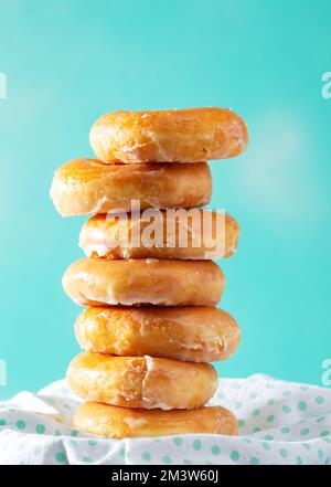 Stack of glazed doughnuts on an aqua colored background with copy space Stock Photo