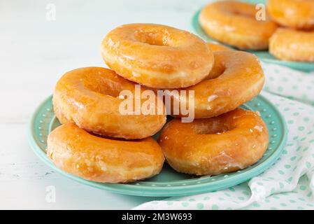 Glazed doughnuts on an aqua colored plate with a matching linen; copy space Stock Photo