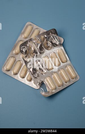 close up of white pills capsules on blue background, top view Stock Photo