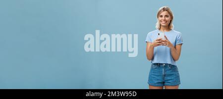 New phone is fantastic. Portrait of satisfied happy young modern blond woman in trendy outfit with blond short haircut smiling joyfull from delight Stock Photo