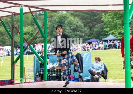 Young teenage man wearing scottish kilt performs in the scottish highland dancing competition at Tomintoul highland games in summer 2022,Scotland,UK Stock Photo