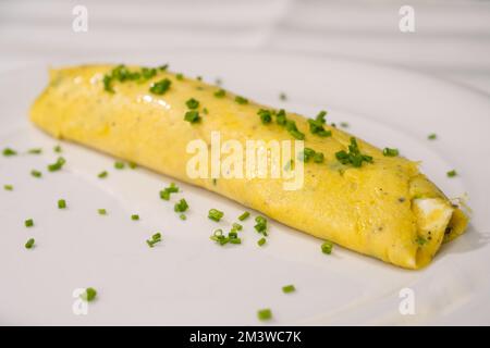 French Chives Omelette, Runny or Baveuse Eggs with Green Herbs on a White Plate Stock Photo