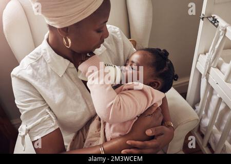 My precious little girl. an adorable baby girl drinking out of her baby bottle while she sleeps in her mothers arms at home. Stock Photo