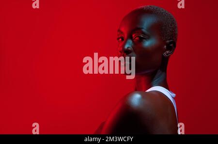 Visualize your highest self and show up as her. Red filtered shot of a beautiful young woman posing in the studio. Stock Photo