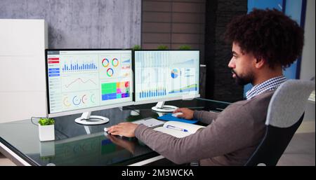 African Data Analyst Man Using Spreadsheet On Computer Stock Photo