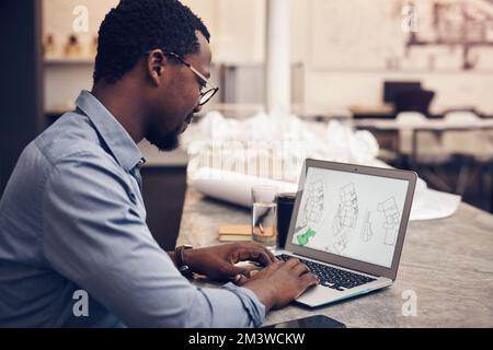 Working his magic. a handsome young male architect working on a laptop in a modern office. Stock Photo