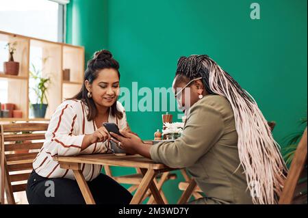 Bestie catch up time is the best time. two young women using a smartphone together at a cafe. Stock Photo