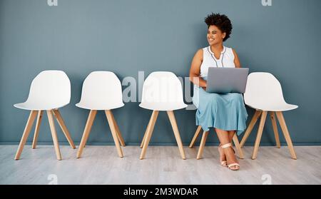 I cant wait to go in and give it my best shot. Studio shot of an attractive young businesswoman smiling thoughtfully while using a laptop against a Stock Photo