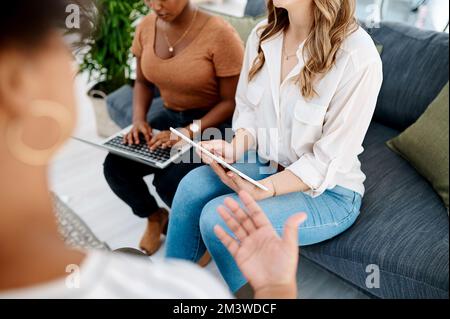 Working hard to stay ahead of the game. Closeup shot of two unrecognisable businesswomen using a laptop and digital tablet during a meeting in an Stock Photo