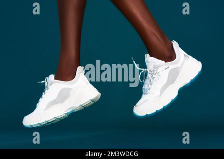 Keeping fit in style. an unrecognizable sportswoman wearing her sneakers before working out against a dark background in the studio. Stock Photo