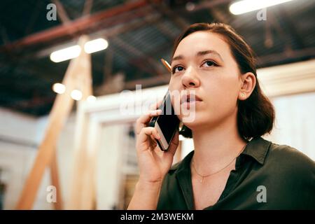 Thats quite a big order...a female carpenter talking on her cellphone while standing in her workshop. Stock Photo