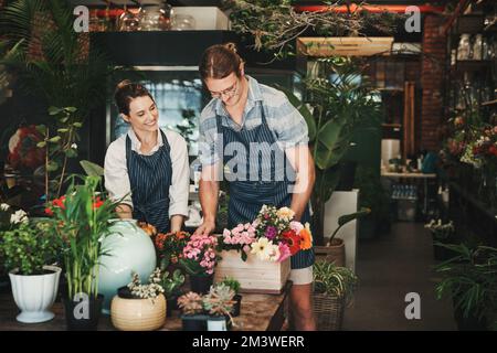 Flowers are our expertise. two young florists working together inside their plant nursery. Stock Photo